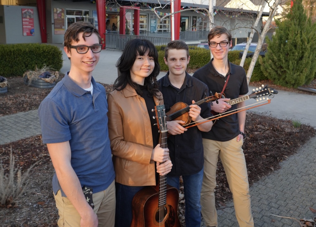 Sandy Point bluegrass band posing outdoors with guitar, mandolin, and fiddle